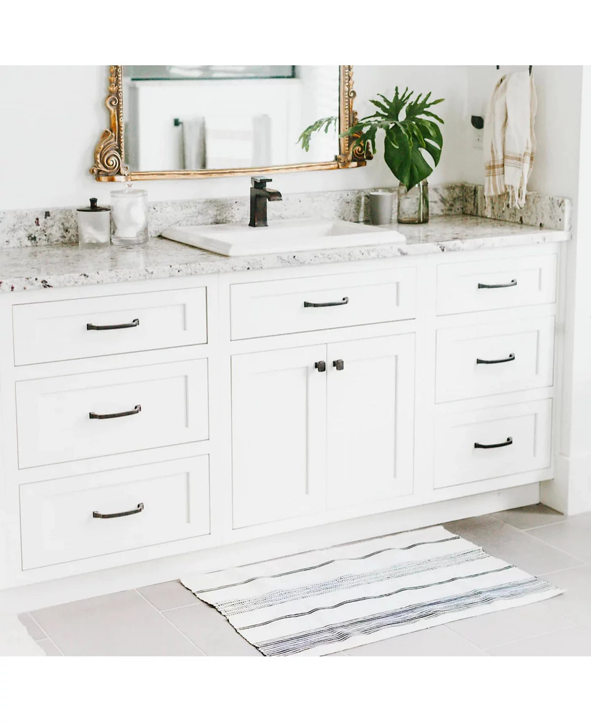 The Aden bath mat in front of a white bathroom vanity