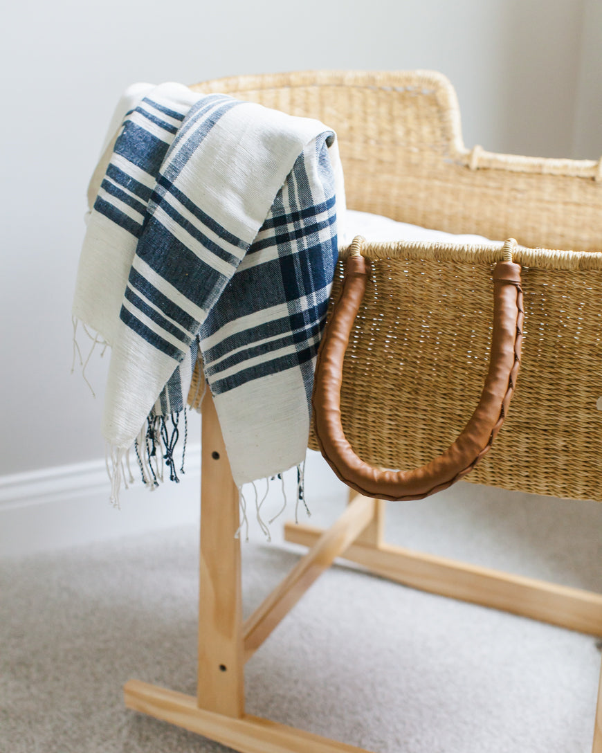 The Cabin Hatch throw draped over a woven basket on a wooden stand