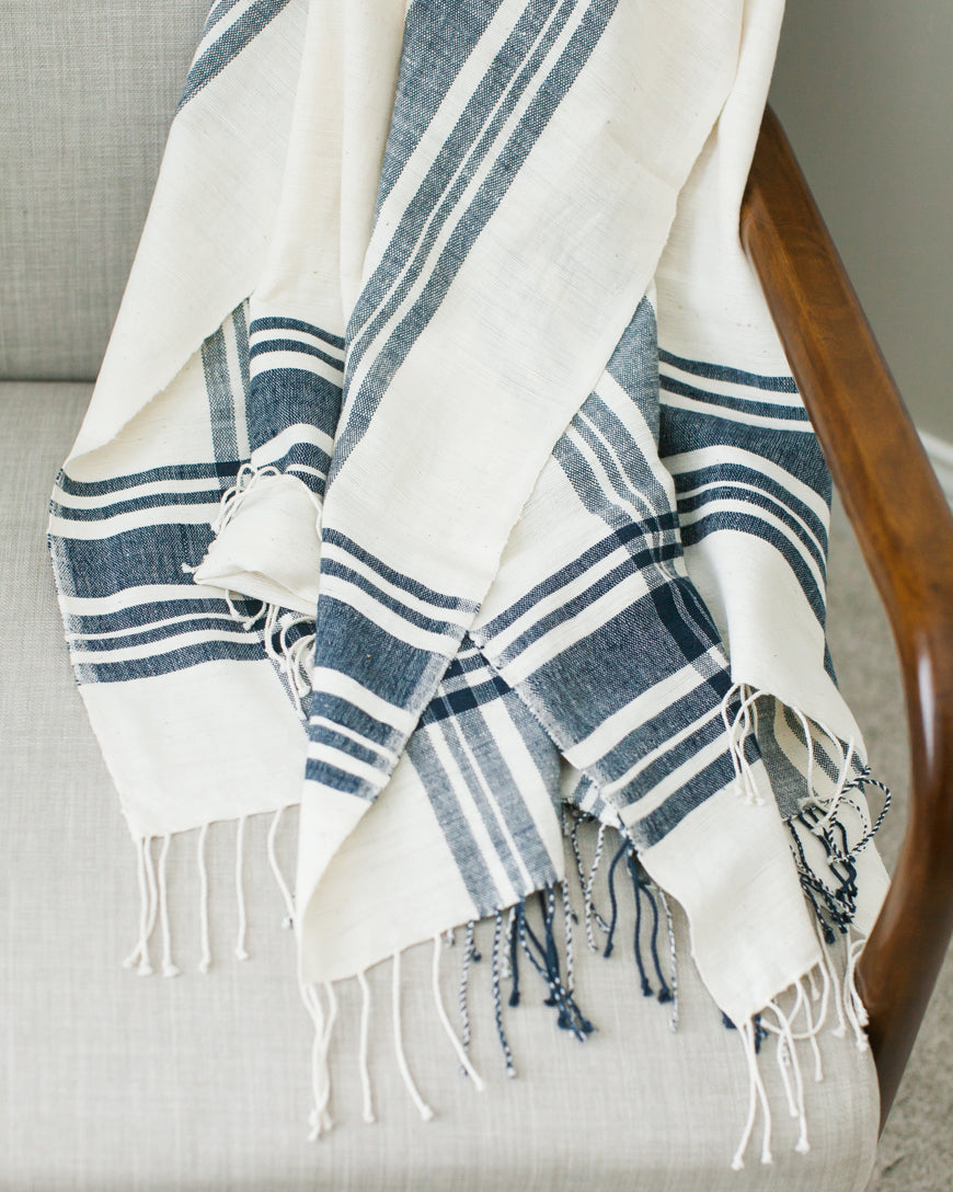 The Cabin Hatch throw in ivory and navy stripe draped over a wood armchair