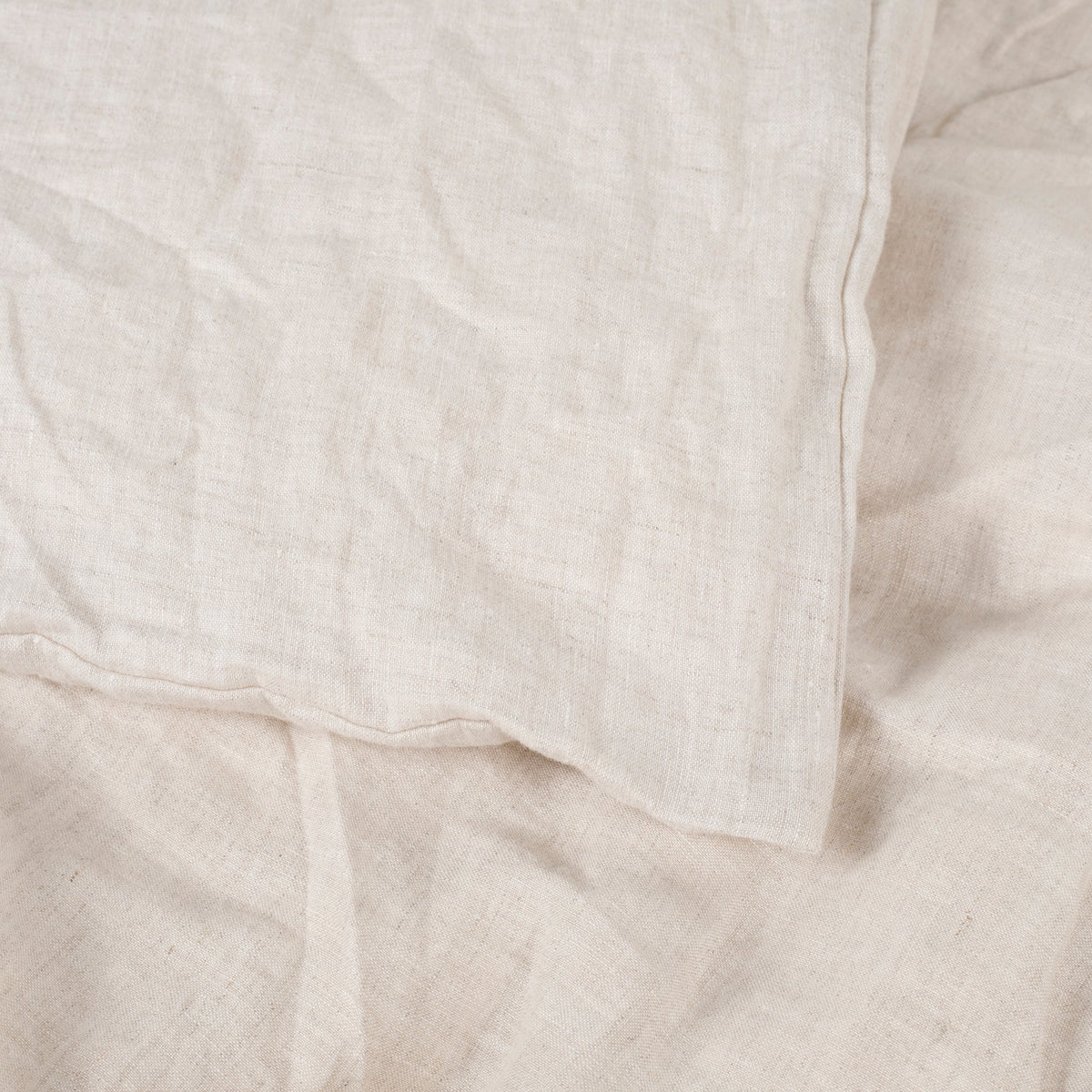 Close-up of the greige natural linen duvet cover showing its soft, rumpled texture