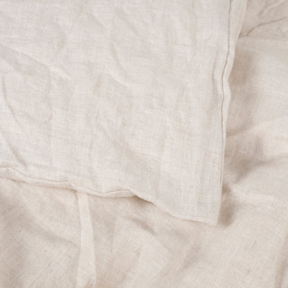 Close-up of the greige natural linen duvet cover showing its soft, rumpled texture