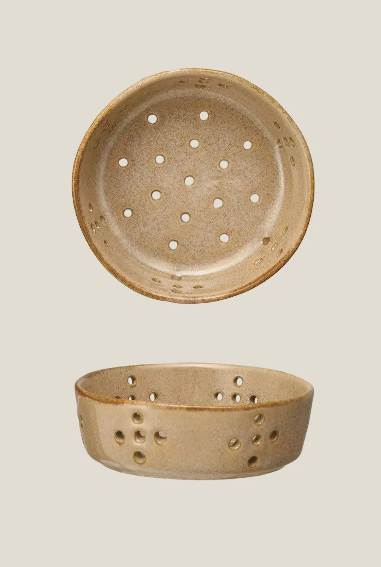 Beige stoneware berry bowl with drainage holes and a brown rim, shown from above and from the side