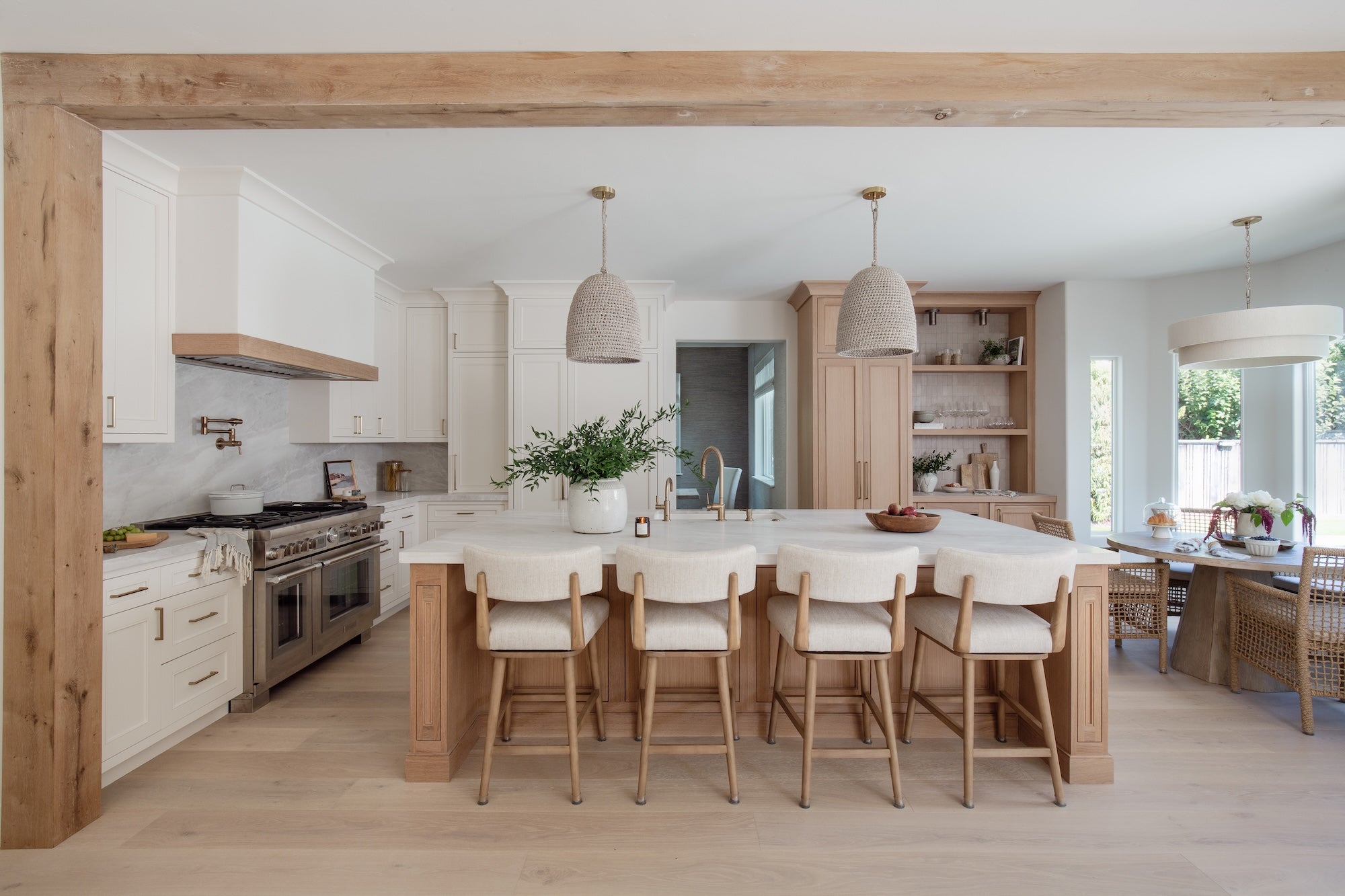 Modern kitchen with wooden island and stools, adjacent to a dining area.