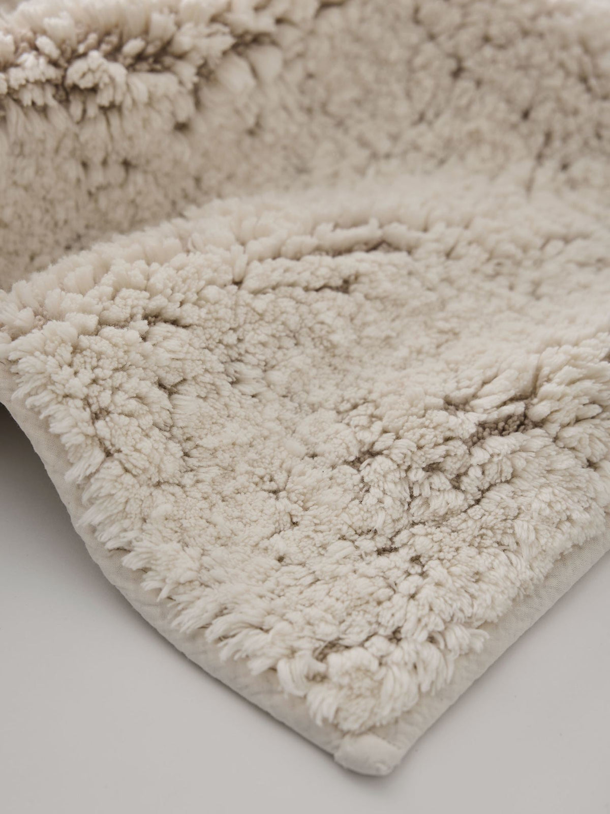 Close-up of the Elsa bath mat's dense, soft off-white cotton and linen pile