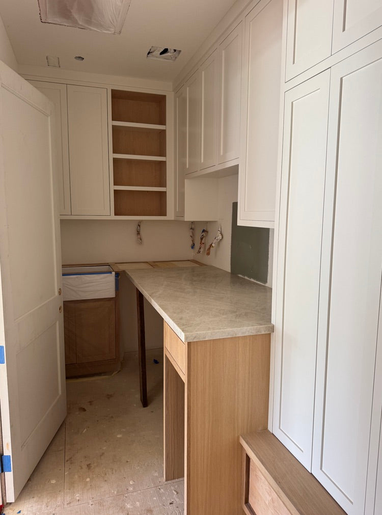 Dover Shores Project butler's pantry with painted white shaker cabinetry, white oak base accents, and natural stone slab countertop
