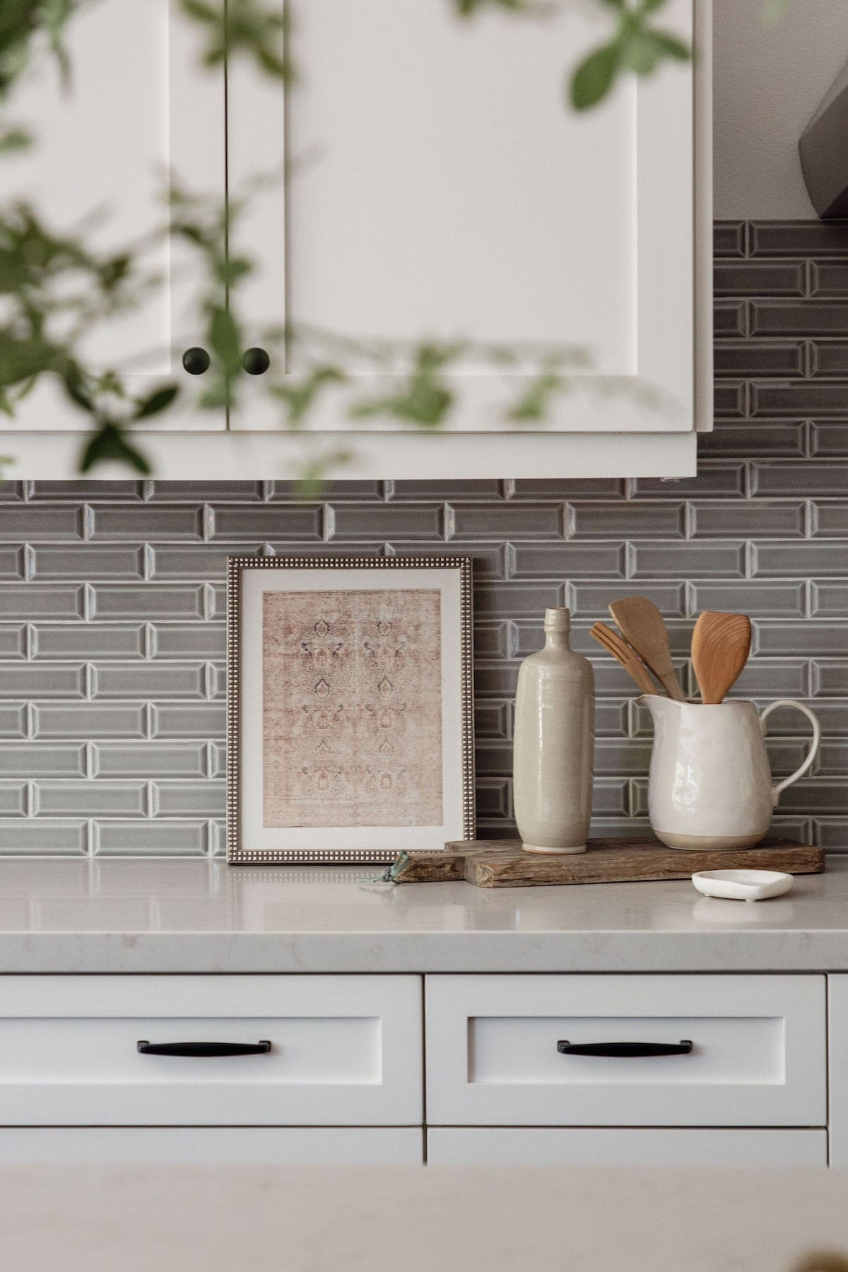 White kitchen with gray brick-set tile backsplash styled with framed textile art and stoneware in the San Juan Spanish project, San Juan Capistrano, California — Joey Snow Design Co.