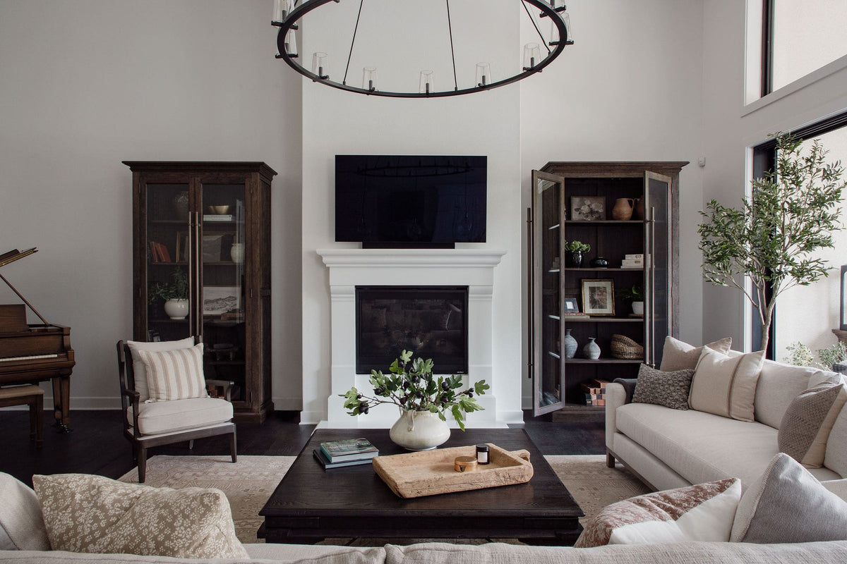 Two-story living room with iron ring chandelier, plaster fireplace, dark wood cabinets, and grand piano in the San Juan Spanish project, San Juan Capistrano, California — Joey Snow Design Co.