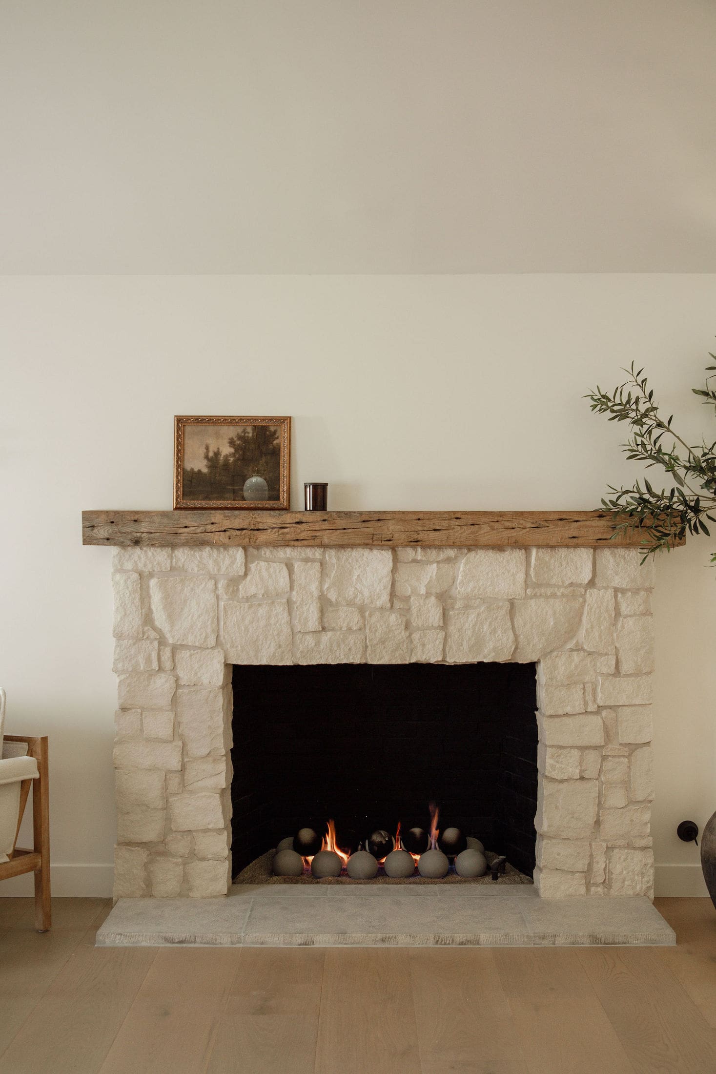 Living room stone fireplace with rustic wood mantel and gas fire set beneath framed artwork.